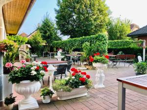 a patio with white vases filled with red and white flowers at Hotel Carolinensiel Doan in Carolinensiel