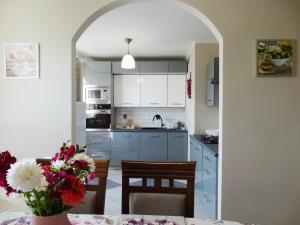 uma cozinha com armários brancos e uma mesa com um vaso de flores em Apartament Zacisze em Jelenia Góra