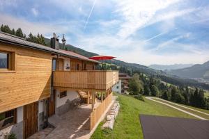 uma casa com uma varanda com um guarda-chuva vermelho em Ferienwohnung Bergwelt em Kirchberg in Tirol