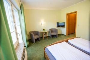 a hotel room with a bed and a table with chairs at Pension Haus am Walde in Schmallenberg