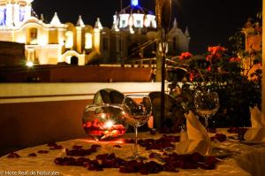 a table with two wine glasses on a table with a building at Hotel Real de Naturales in Cholula