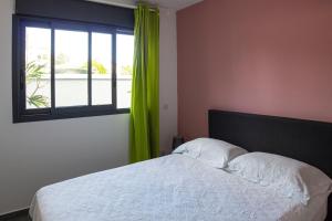 sypialnia z łóżkiem i oknem z zielonymi zasłonami w obiekcie T2 - 64m2 - Résidence Georgette w mieście Terre Sainte