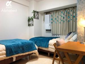 Duas camas num quarto com uma mesa e uma secretária. em Scarl Matsunawa / Vacation STAY 49770 em Takamatsu
