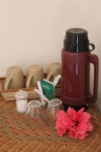 una cafetera roja y algunas tazas y flores en Gite des Acacias, en Union Vale