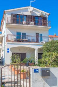 a large white building with balconies and plants at Apartmani Jadranka in Primošten