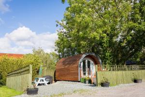 a small wooden building with a table and a fence at Buttles Glamping Pod in Saundersfoot