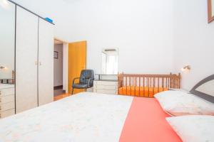 a bedroom with a bed and a chair at Apartmani Jadranka in Primošten