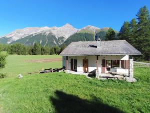 a small house in a field with mountains in the background at Chesa Piz d'Esan in S-chanf