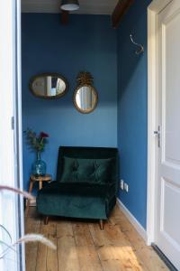 um sofá verde num quarto azul com dois espelhos em Mini appartement De Fabriek em Nijmegen