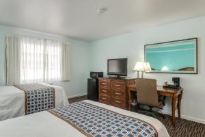 a hotel room with two beds and a desk and a television at Pacifica Beach Hotel in Pacifica