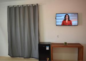 a television hanging on a wall with a woman on it at Pousada Village Sonhos Camocim in Camocim