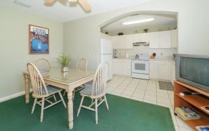 cocina con mesa y sillas y TV en Steps to #1 Beach in America Siesta Beach!, en Siesta Key