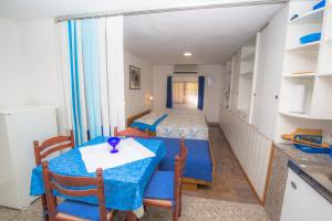 a small room with two beds and a table and chairs at Apartmani Jadranka in Primošten