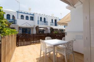a white table and chairs on a patio with a building at bungalow with terrace near the beach in San Bartolomé de Tirajana