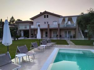 a house with a swimming pool with chairs and umbrellas at Garda Bloom Holiday Apartments in Padenghe sul Garda