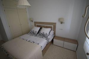 Un dormitorio pequeño con una cama con sábanas blancas. en Apartamento acogedor en lugar inmejorable, en Sanlúcar de Barrameda 25 fotos más