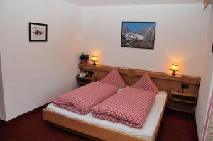 um quarto com uma cama com almofadas vermelhas e brancas em Pension Belvedere em Galtür