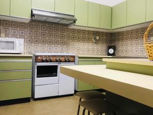 eine Küche mit grünen Schränken und einem weißen Herd mit Backofen in der Unterkunft Casa do Nini in Amarante