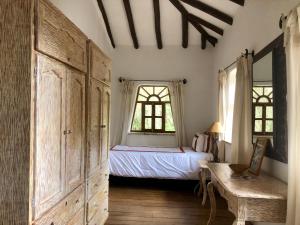 a bedroom with a bed and a dresser and two windows at Las Casitas del Arco Iris in Urubamba