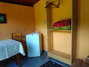 a room with a white refrigerator and a table and a table and a table at Pousada Pedra da Gávea in Visconde De Maua