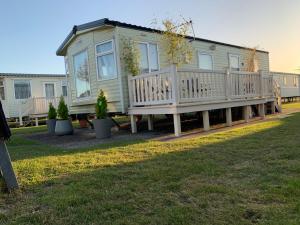 a mobile home with a porch and a deck at Forest & beach access Naish park in New Milton