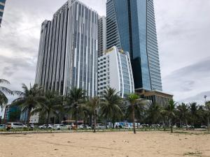 a beach with palm trees and tall buildings at Căn hộ nghỉ dưỡng Mường Thanh apartment in Da Nang
