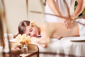 a woman laying on a bed in a massage room at Hotel International in Baile Felix