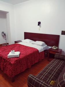 Habitación de hotel con cama con colcha roja en Hostal Inversiones Huachipa en Lima