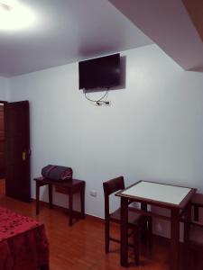 sala de estar con mesa y TV en la pared en Hostal Inversiones Huachipa, en Lima