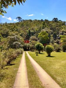 un camino a través de un parque con una casa roja en el fondo en Pousada Pedra da Gávea, en Visconde De Maua