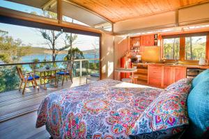 a bedroom with a bed and a kitchen and a balcony at Free Spirit Pods in Barnes Bay
