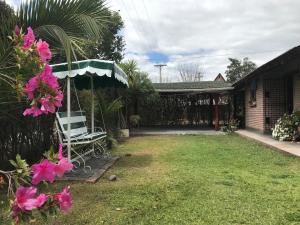 Un patio con una silla, una sombrilla y flores rosas en Las Azaleas Yala, en Yala