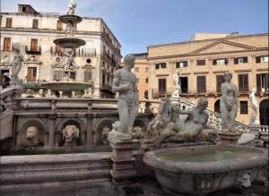 uma fonte com estátuas em frente a um edifício em Dietro la Cattedrale em Palermo