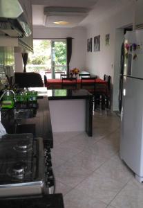 a kitchen with a refrigerator and a living room at Apartamento Bay Conceicao in Bombinhas