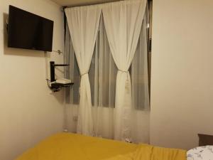 a bedroom with a bed and a window with curtains at Carmen con Argomedo, PARKING por pagar in Santiago