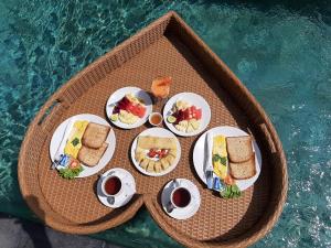ein Tablett mit Essen auf einem Tisch neben einem Pool in der Unterkunft The Satya Villa in Ubud