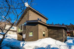 a house with snow in front of it at SOLAR CHALETS by Hakuba Hotel Group in Hakuba