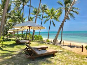 two picnic tables and umbrellas on the beach at Mali House in Mae Nam