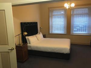 a bedroom with a bed and two windows at The Macquarie Hobart in Hobart