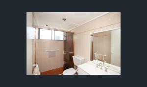 Un baño con inodoro, lavabo y espejo. en Spectrum Holiday Apartments, en Gold Coast 40 fotos más