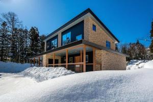 uma casa de tijolos na neve na neve em Phoenix Chalets by Hakuba Hospitality Group em Hakuba