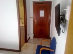 pasillo con puerta y silla azul en una habitación en Pensión Arroniz, en Arróniz