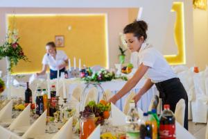 a woman standing in front of a table with food at Hotel Arkada in Rawa Mazowiecka