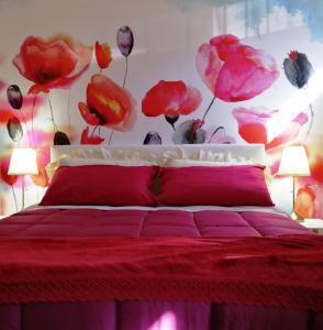 um quarto com uma cama vermelha com flores na parede em A casa di Vince Monteaperti em Montaperti