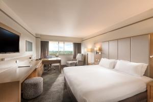 una camera d'albergo con un grande letto bianco e una scrivania di Stamford Plaza Adelaide a Adelaide