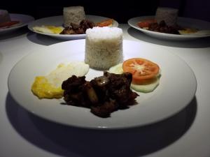 a plate of food on a table with rice at RNR Suites in Legazpi