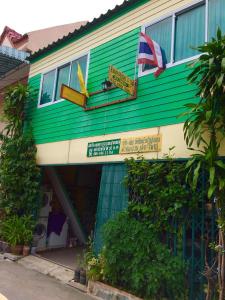 un edificio verde e bianco con le bandiere di PEE HOMESTAY LOPBURI a Ban Tha Krayang