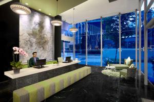 a man sitting at a desk with a laptop in a lobby at Citadines Fusionopolis Singapore in Singapore