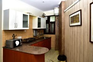 a kitchen with white cabinets and a counter top at 2BHK Comfortable Furnished Serviced Apartments in Hauz Khas - Woodpecker Apartments in New Delhi