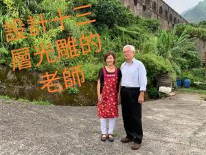 a man and a woman standing in front of a wall at 13F Homestay in Jiufen